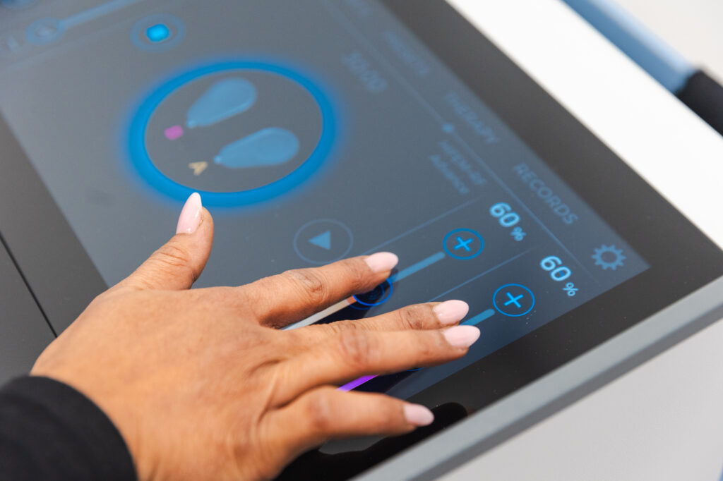 Close-up of a professional using a touch screen to adjust the settings for Emsculpt NEO skin tightening near Atlanta