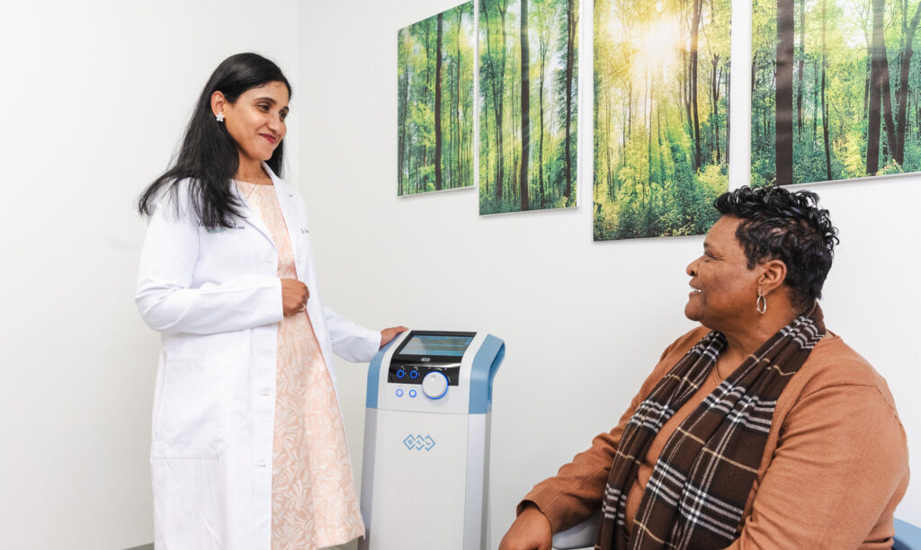 A female medical provider talks with her female patient in a medical office offering Emsella near Brookhaven.