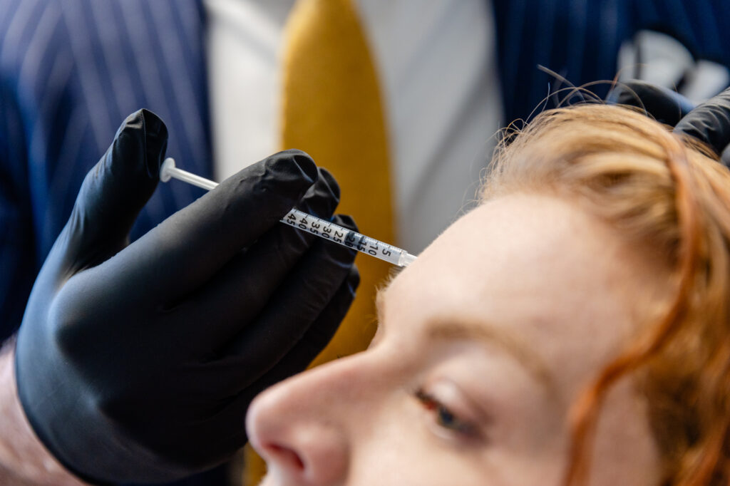 A female patient receives Botox from a professional facialist near you in Sandy Springs wearing black gloves