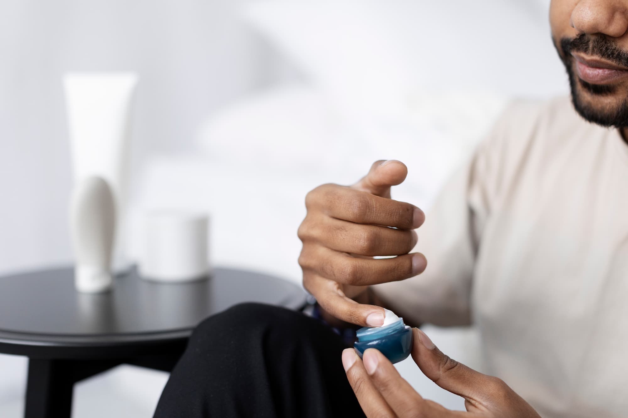 Close up of a man sitting down, getting cream from a small tub to administer his Hormone Therapy Near Brookhaven.