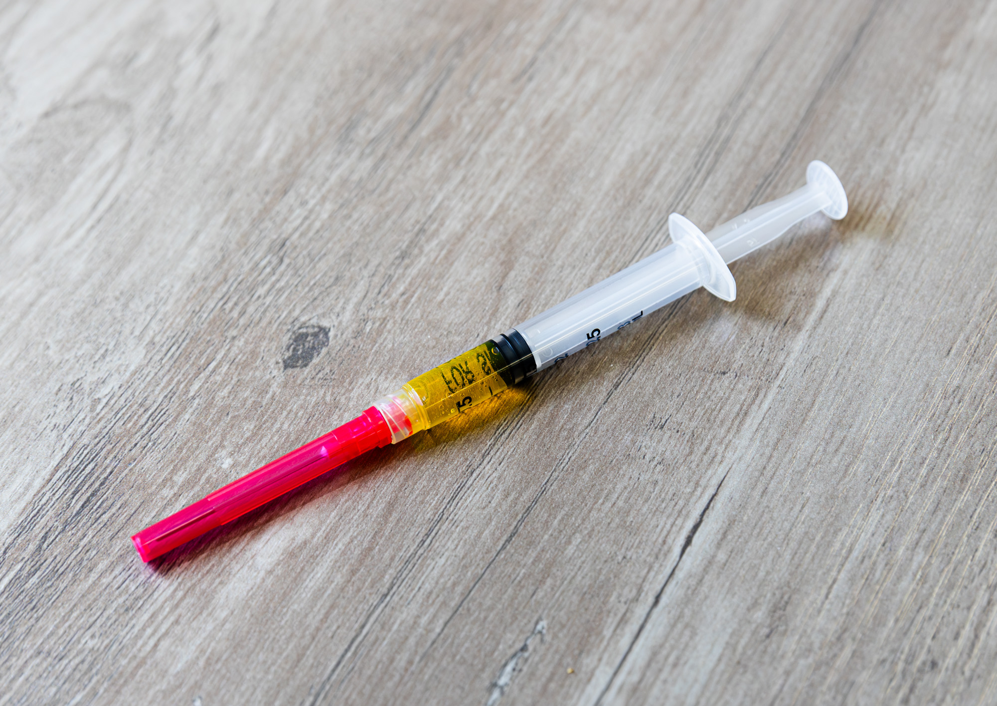 A syringe filled with multivitamins rests on top of a wood surface. A nurse will use it for vitamin D treatments near Brookhaven.